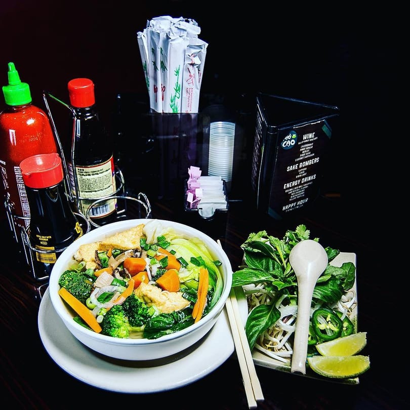 Vegetable pho with tofu, broccoli, carrots, and bok choy, served with fresh herbs and lime.